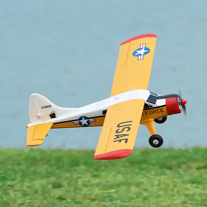 High-quality remote control aircraft with USAF military design, yellow and red color scheme, flying near water with green grass below, ideal for RC aviation enthusiasts.