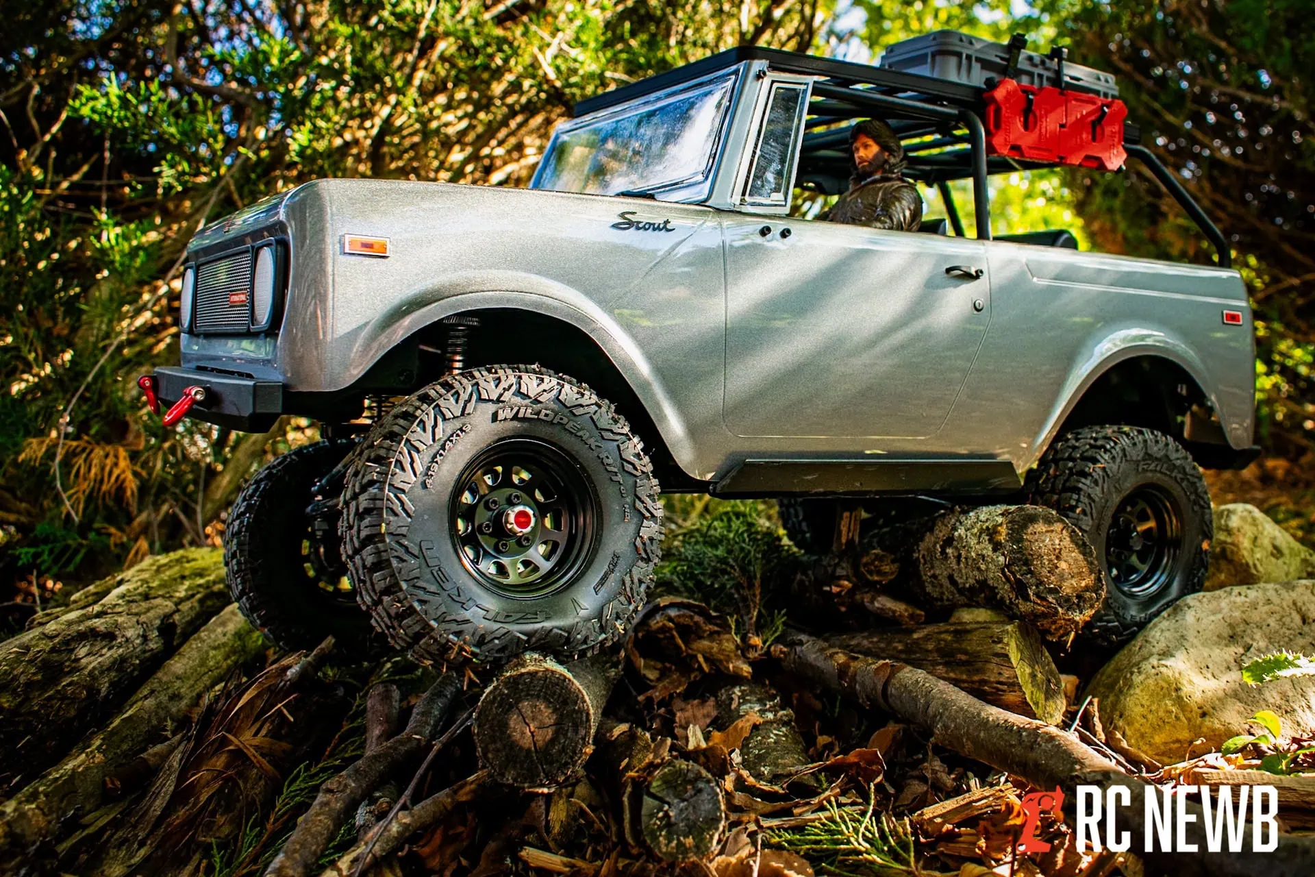 Restoring off-road adventure with a detailed scale model of a vintage Ford Scout vehicle navigating rugged terrain on forest logs. Perfect for RC off-road enthusiasts and scale RC vehicle fans.