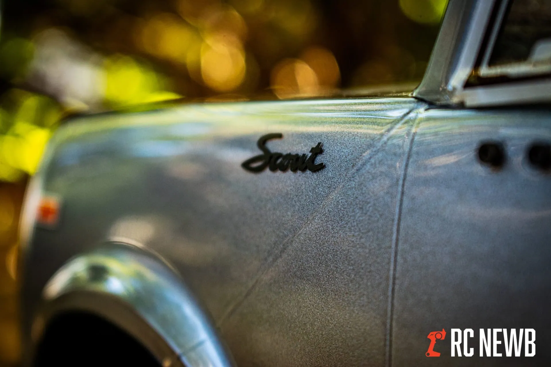 Close-up of a vintage car's metallic exterior with a focus on the "Scout" badge, showcasing classic automotive design and craftsmanship, perfect for RC car enthusiasts and collectors.