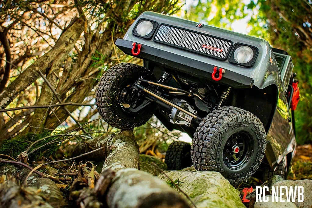 RC off-road truck navigating rocky terrain in a forest setting, showcasing durability and outdoor adventure.