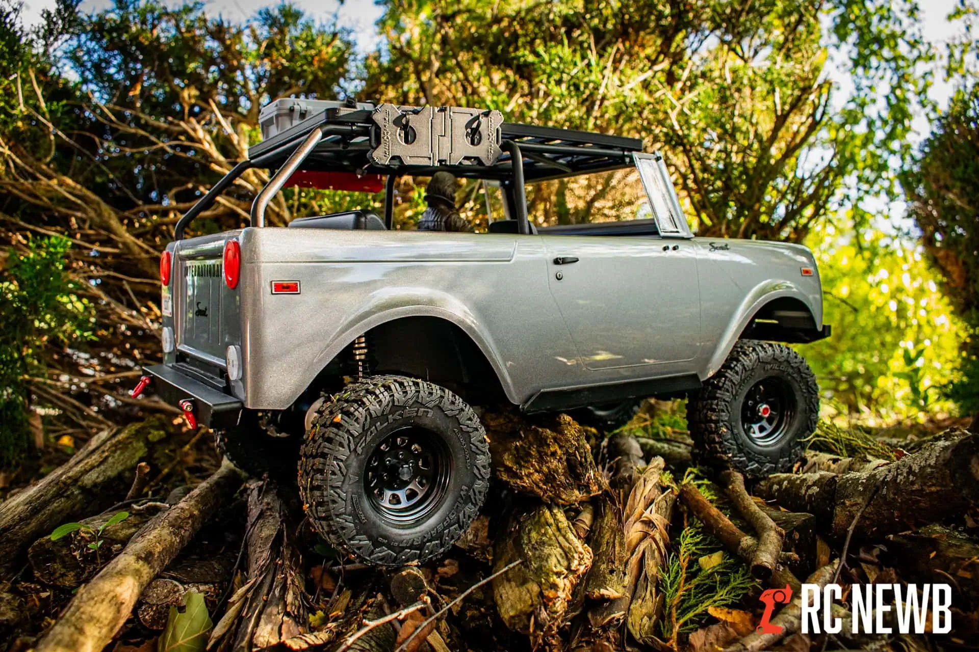 RC off-road truck climbing over logs in a forest setting, showcasing RC Newb's expertise in remote control vehicle customization and off-road RC adventures.