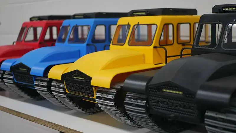 Detailed shot of vibrant red, blue, yellow, and black RC snow vehicles with tracked tracks, perfect for remote control snowcat models and building custom RC vehicles.